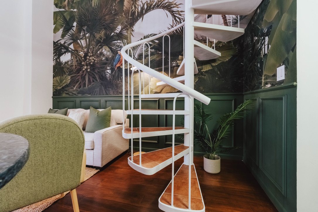 Living area with sofa, armchairs and tropical mural inside Plaza Catedral Loft